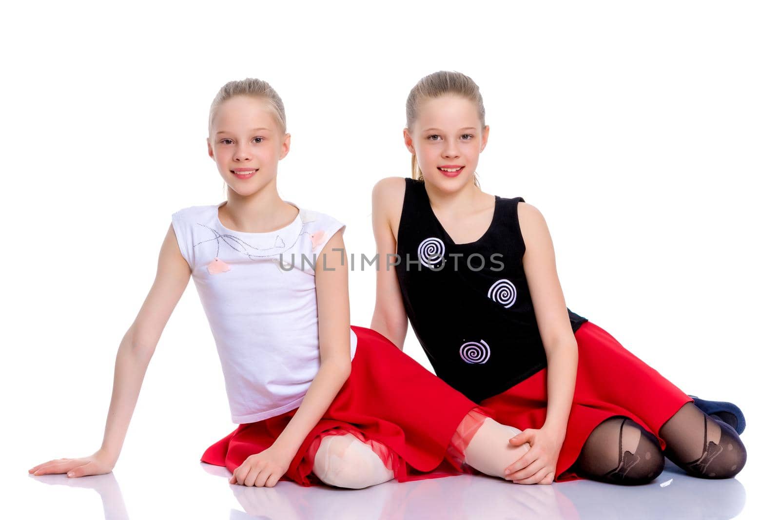 Two beautiful little girls are sitting on the floor in the studi by kolesnikov_studio
