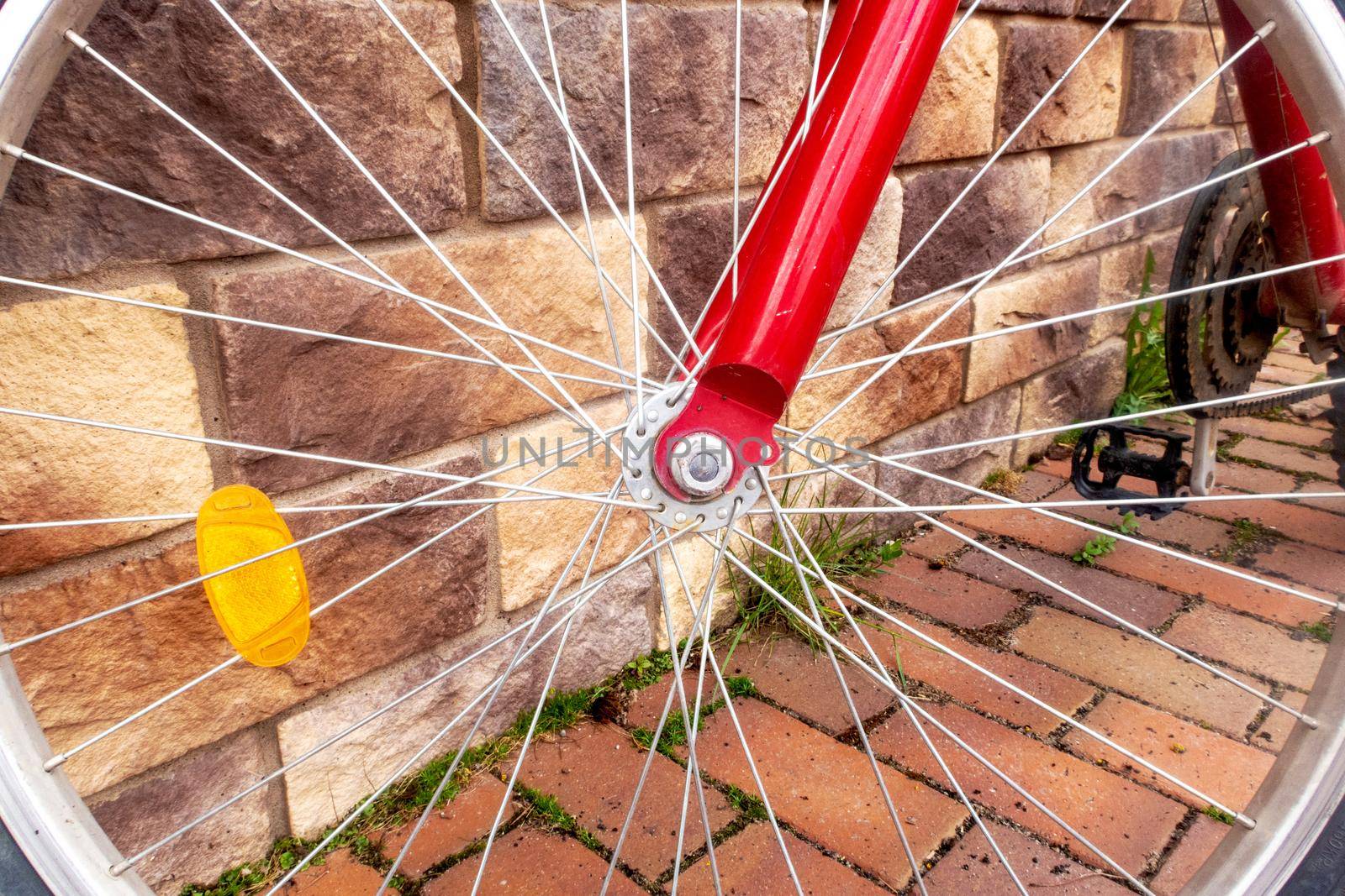 Close-up of a part of a bicycle wheel leaning against a wall of a house. Concept travel, summer vacation.