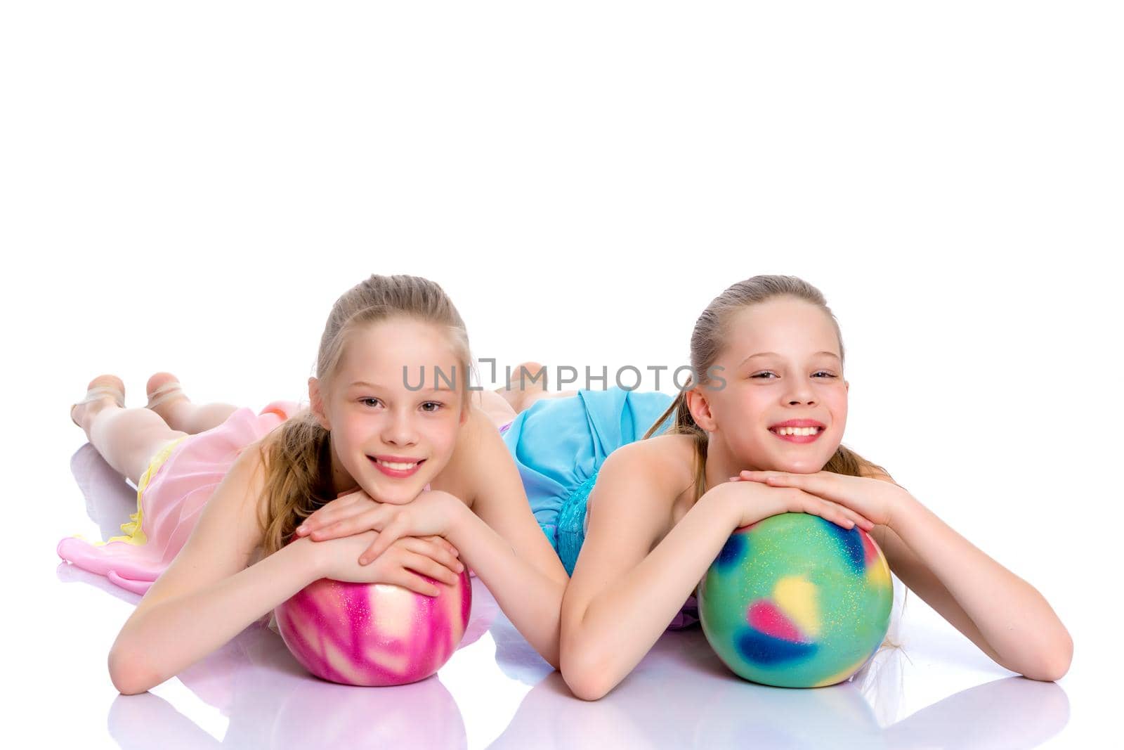 Two cheerful little girls gymnasts in competitions, perform exercises with the ball. The concept of children's sports, fitness, healthy lifestyle. Isolated on white background.