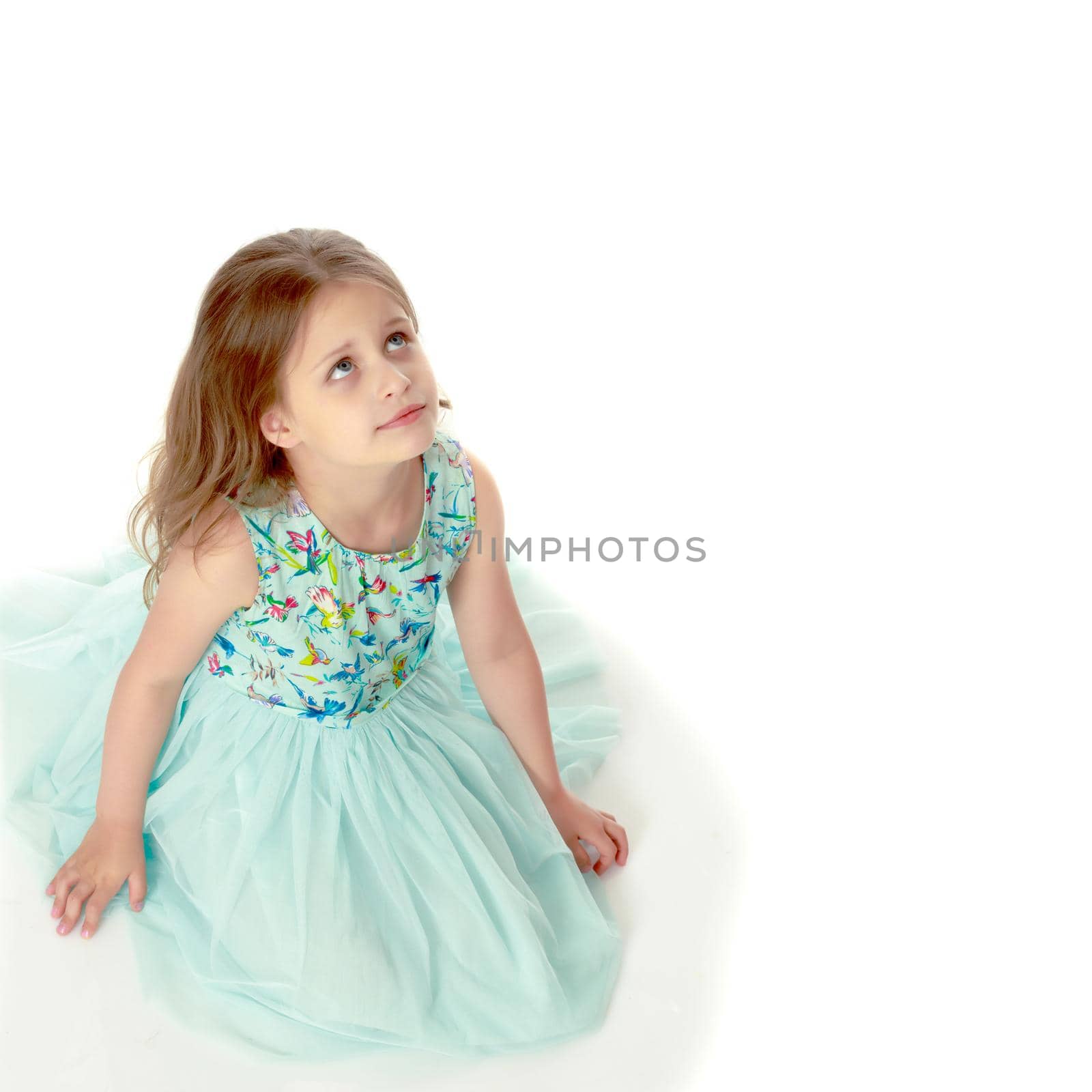 Little girl is sitting on the floor. The concept of a happy childhood. Isolated on white background.