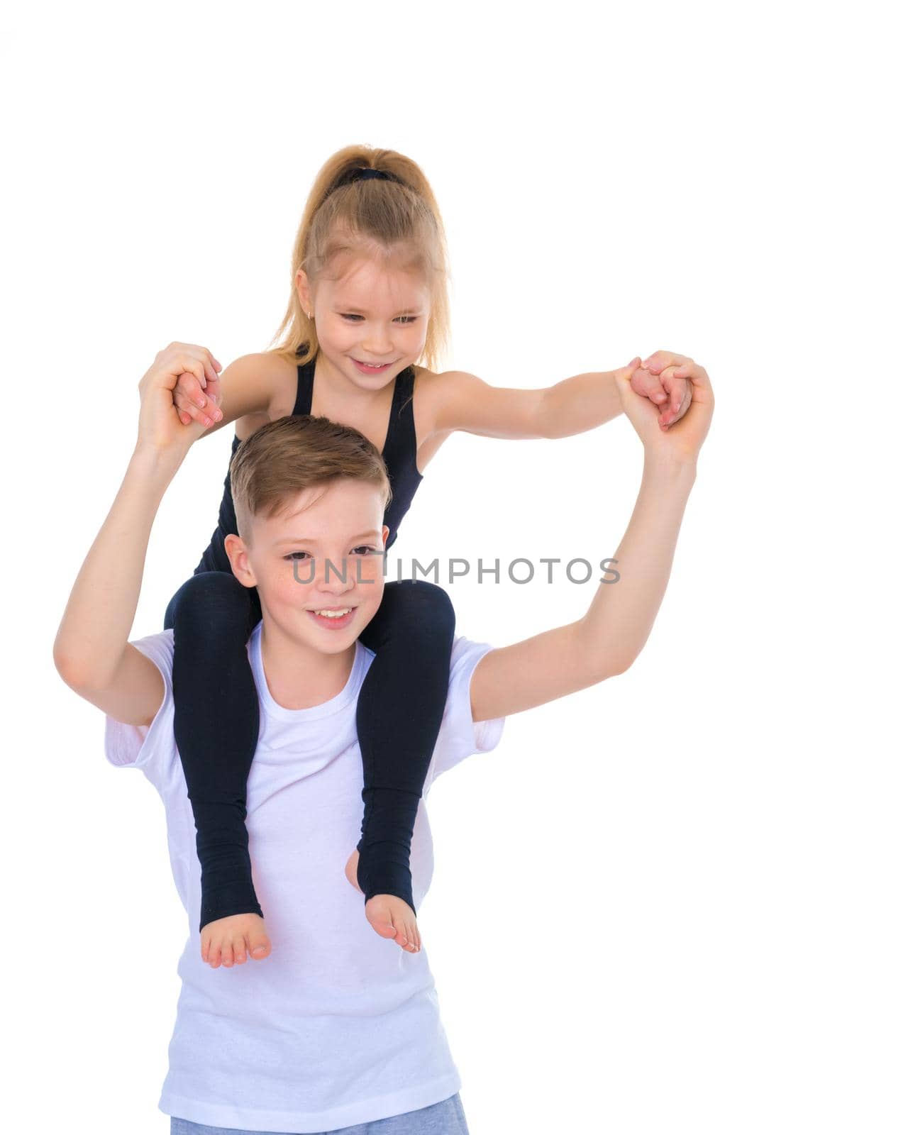 Charming little girl hugging a tall boy with blond hair. A romantic couple is happy with the joint time brought. A happy sister hugs her brother. The concept is a happy childhood. Isolated on white background.