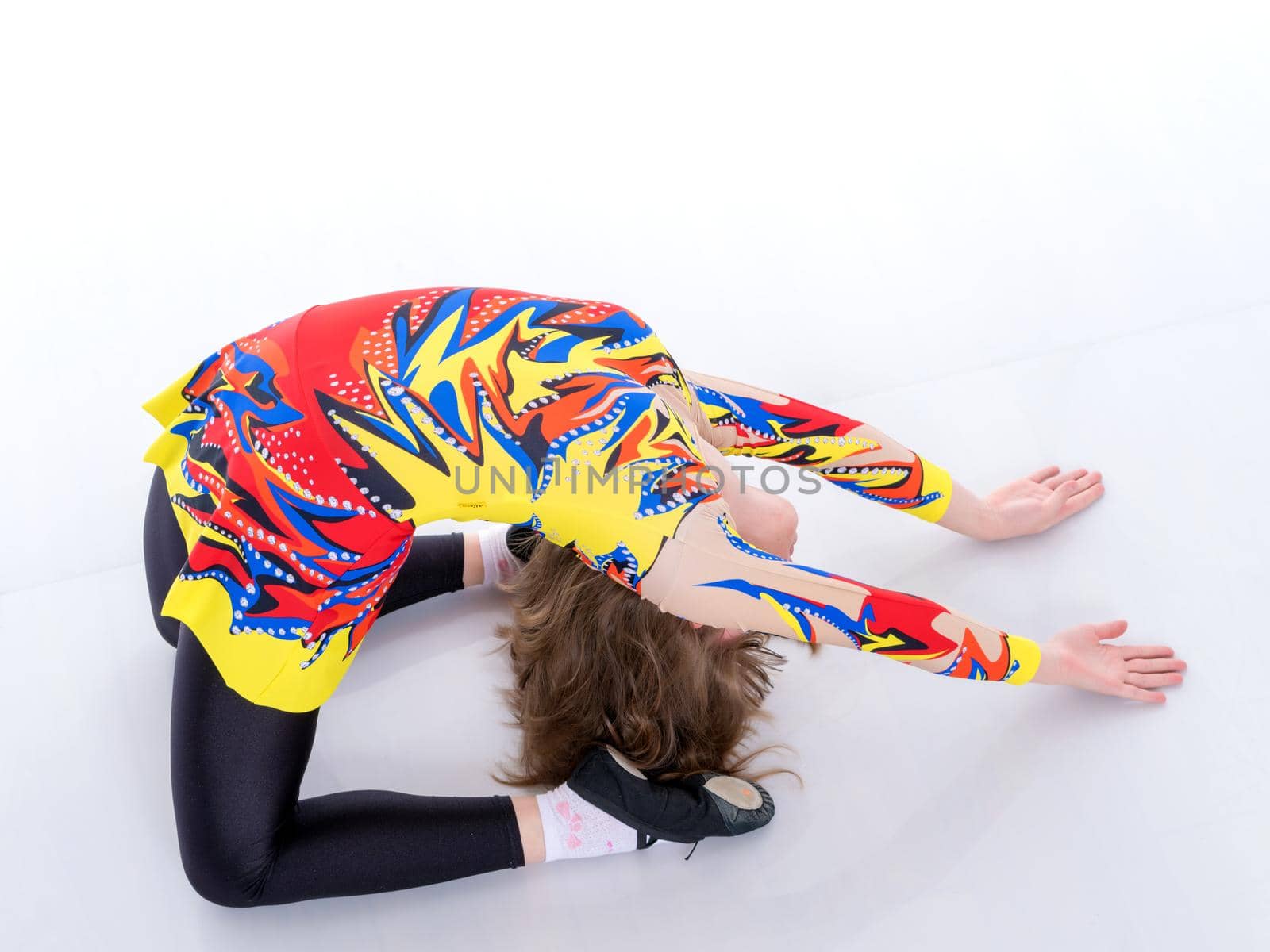 A girl gymnast performs an acrobatic element on the floor. The concept of childhood, sport, healthy lifestyle. Isolated on white background.