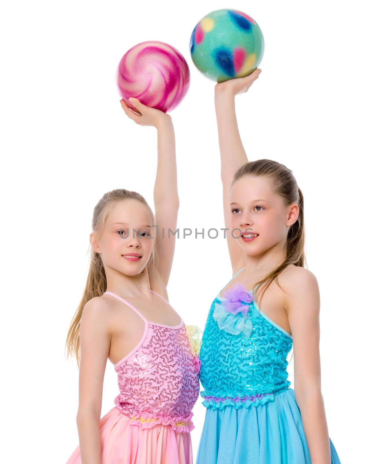 Two cheerful little girls gymnasts in competitions, perform exercises with the ball. The concept of children's sports, fitness, healthy lifestyle. Isolated on white background.