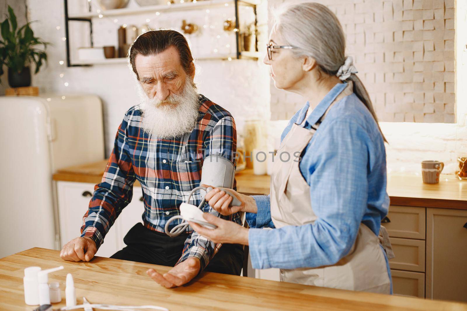 Old couple in a kitchen. Woman in a blue shirt and aprone.