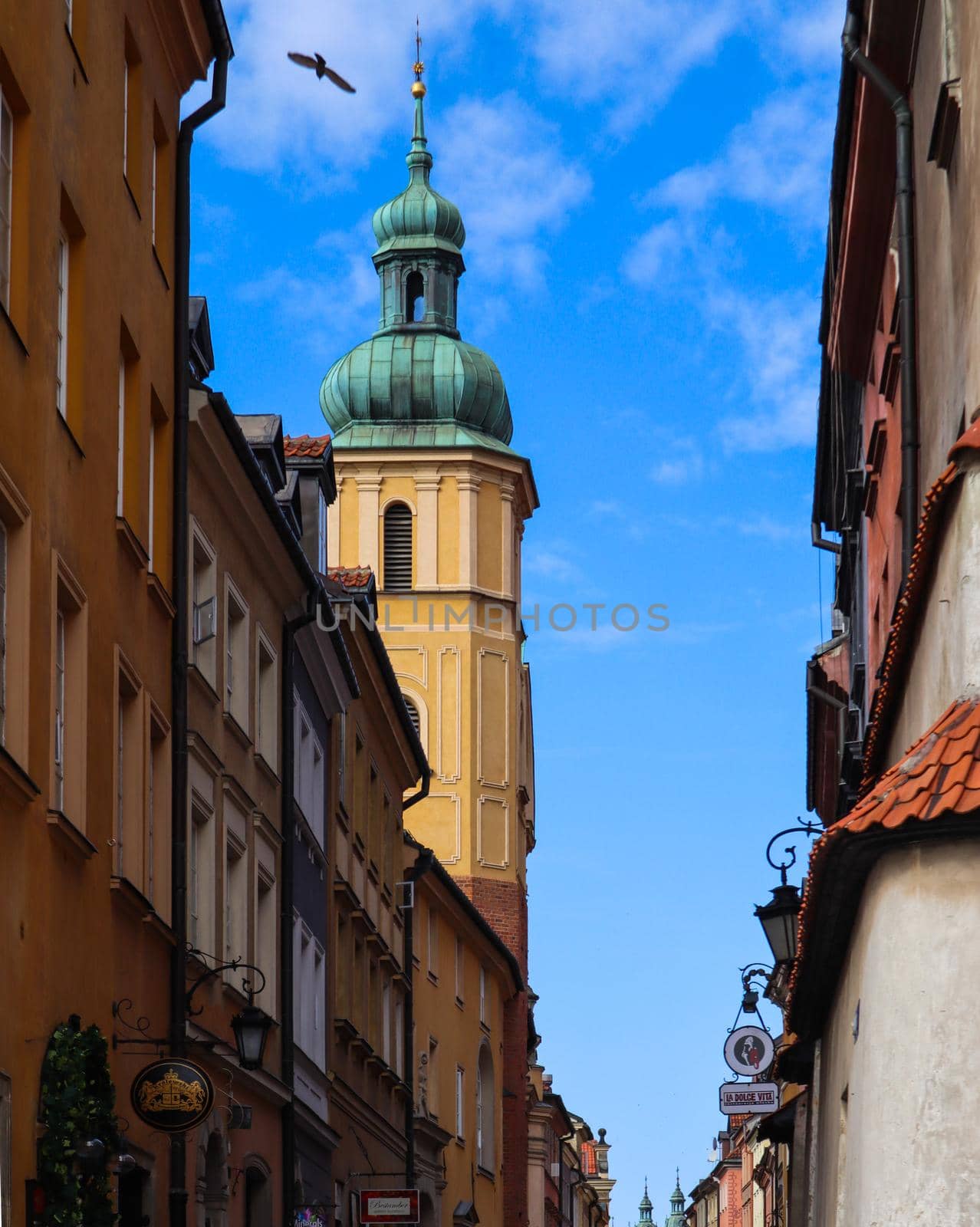 Tower with a spire on the street of Warsaw, Poland against the blue sky with clouds