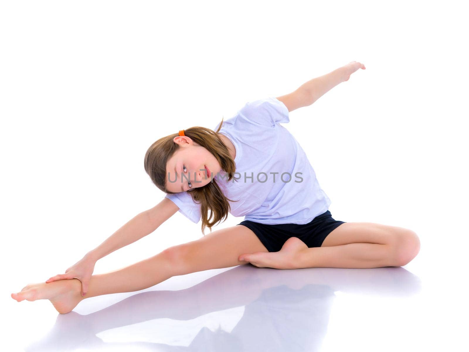 A girl gymnast performs an acrobatic element on the floor. The concept of childhood, sport, healthy lifestyle. Isolated on white background.