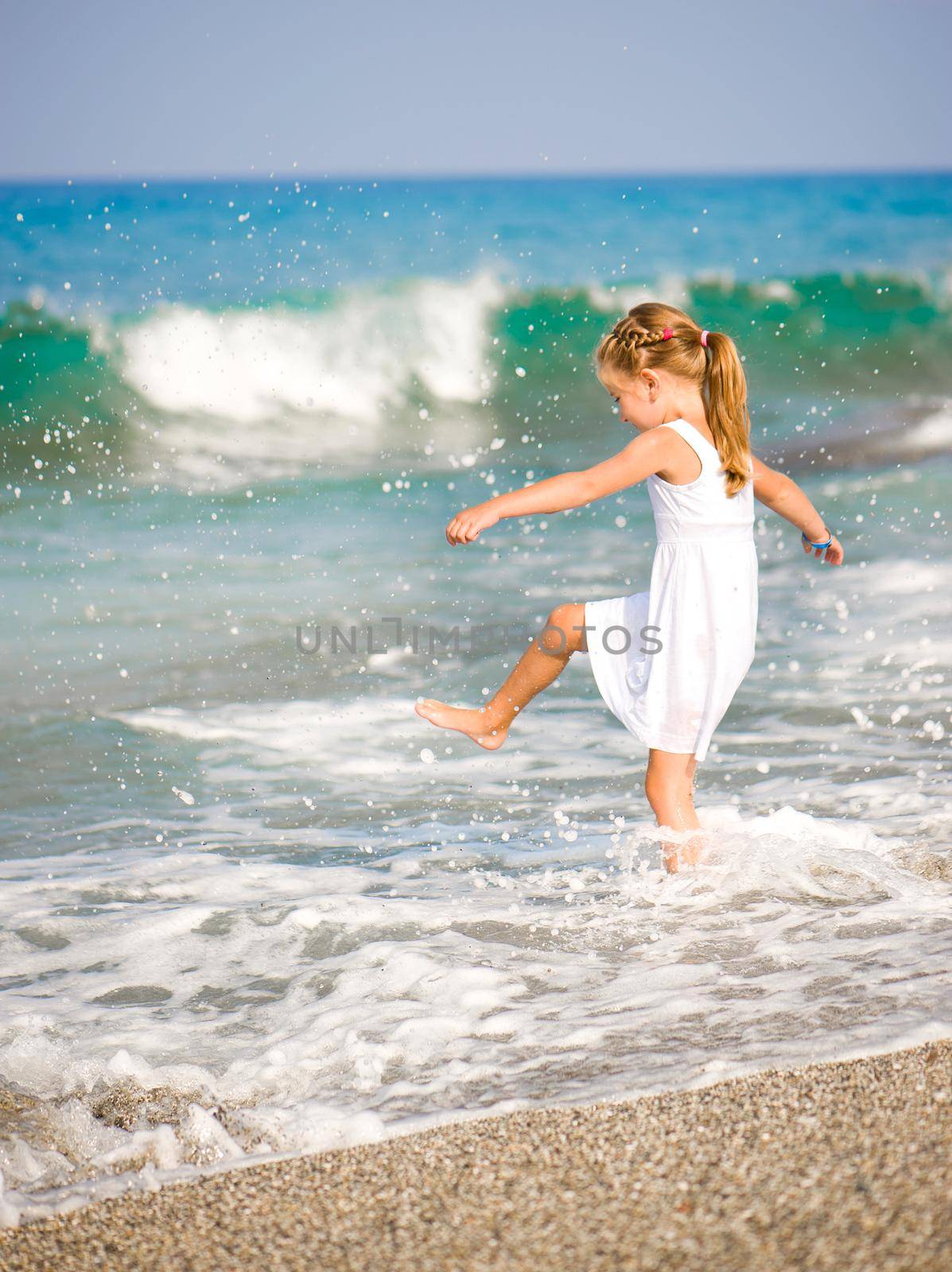 Adorable little girl make a splash on tropical beach vacation