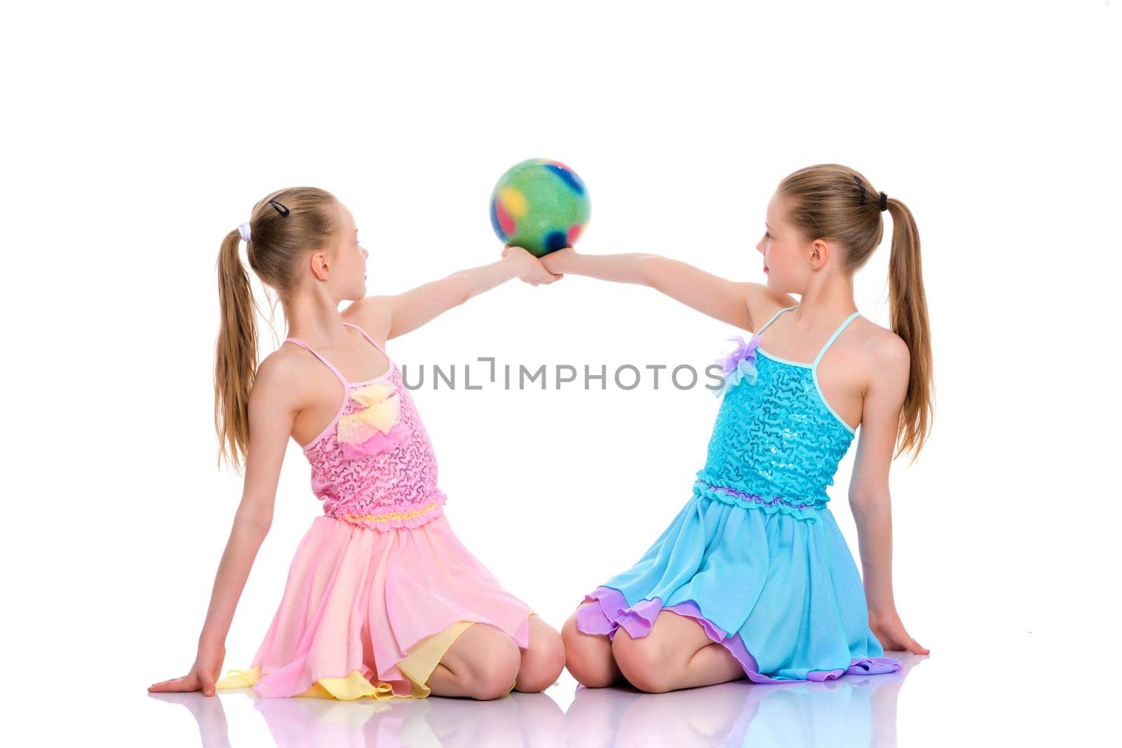 Two cheerful little girls gymnasts in competitions, perform exercises with the ball. The concept of children's sports, fitness, healthy lifestyle. Isolated on white background.