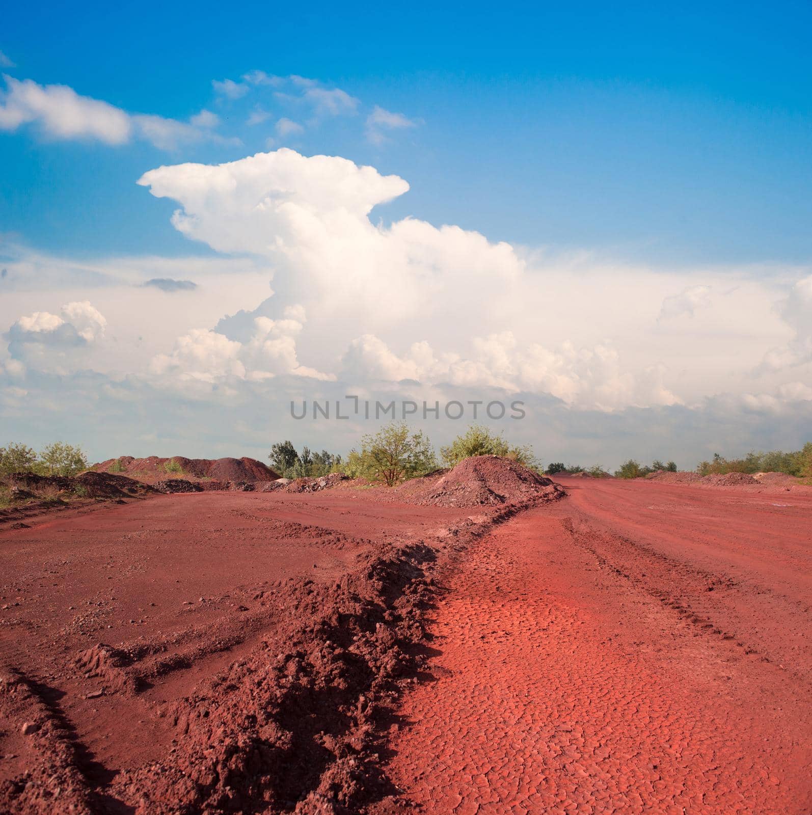 tracks and heaps of red iron oxid land and view on blue sky in Krivyi Rih, Ukraine