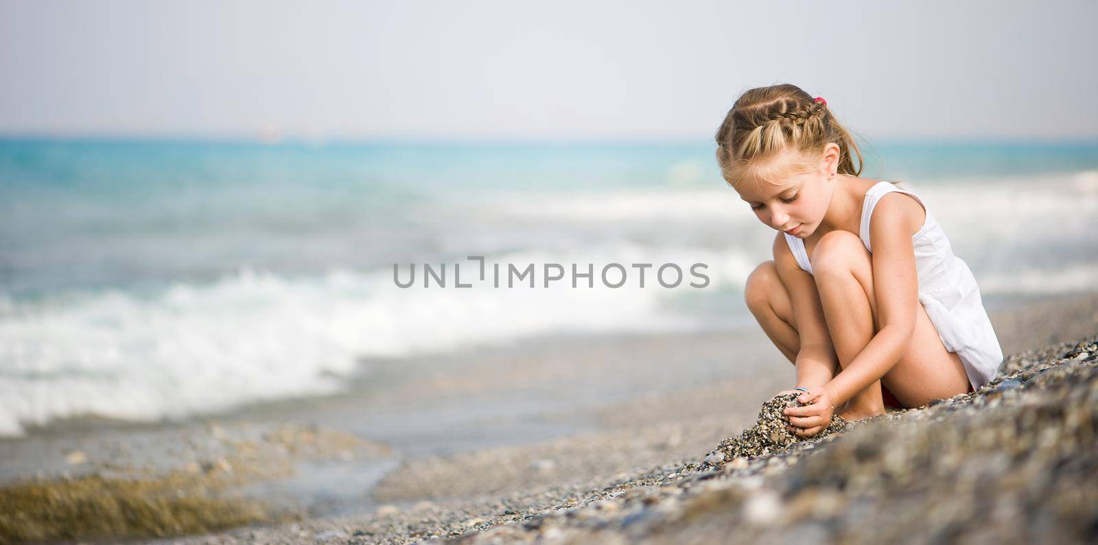 girl builds a house of pebbles on the beach