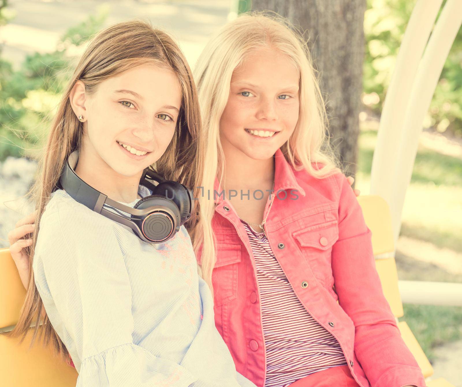 Beautiful smiling girls sitting on the bench friendly hugging