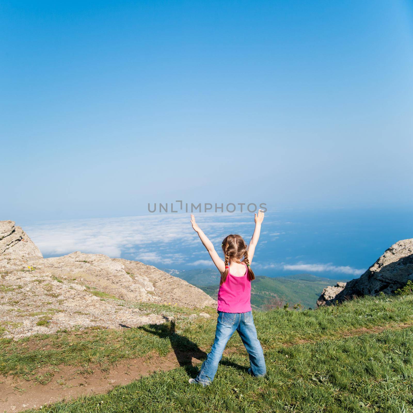 happy little girl on top of a mountain