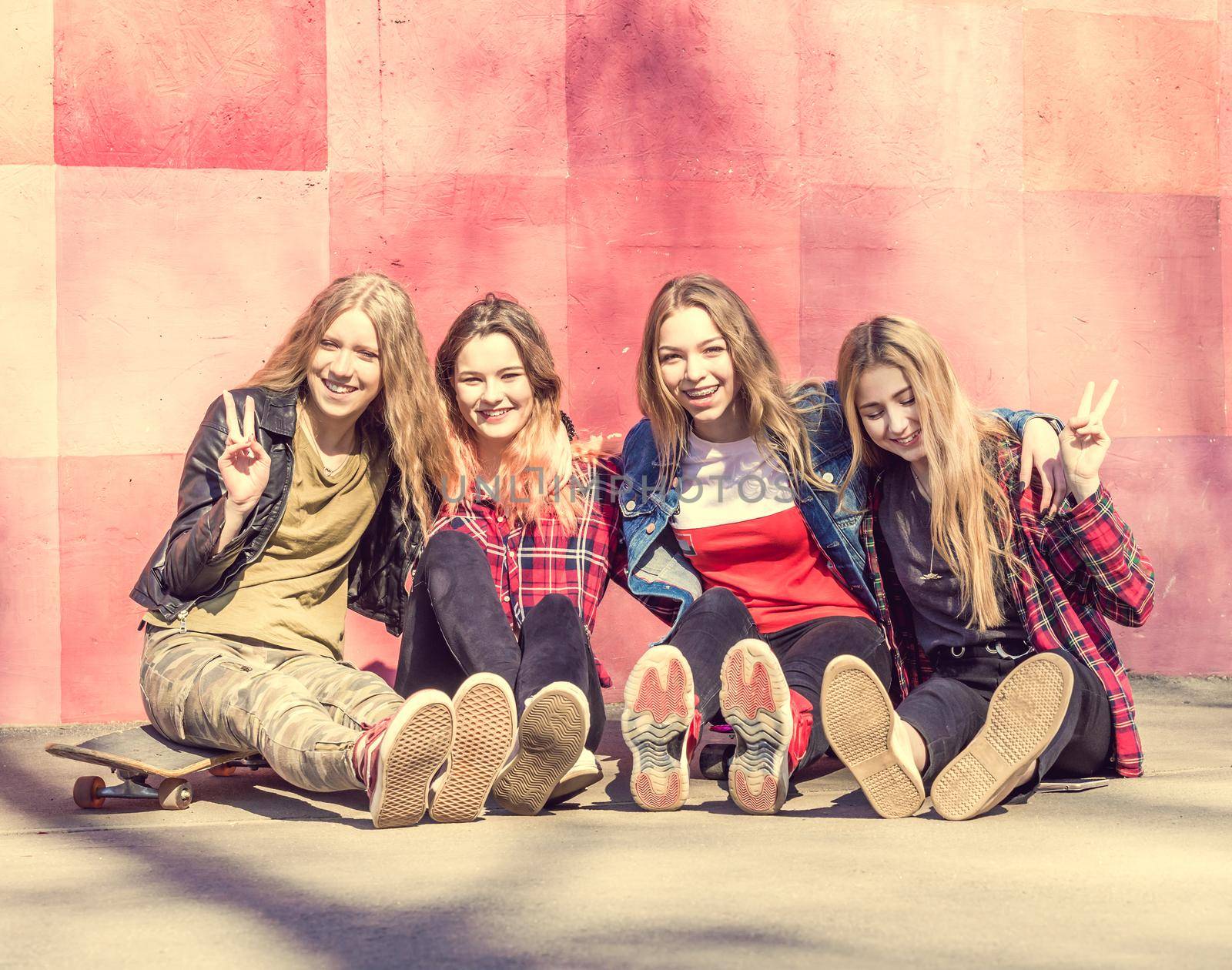Four cool teenage girls with skates posing on camera in the park