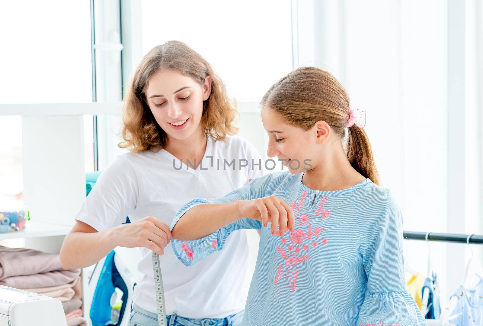 Tailor measuring her client with measuring tape indoors