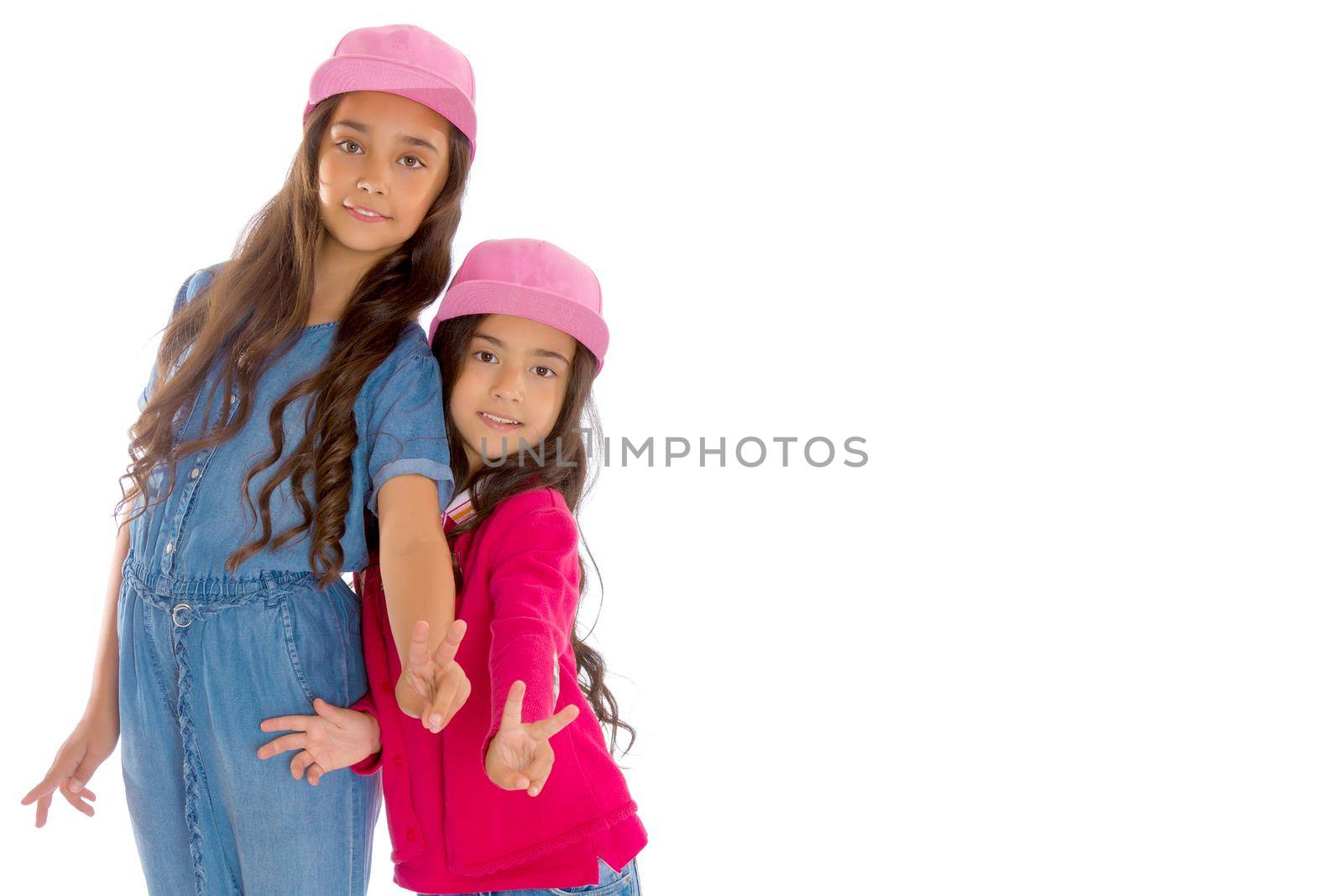 Two cheerful Asian girls show a gesture victoria. The concept of a happy childhood. Isolated on white background.