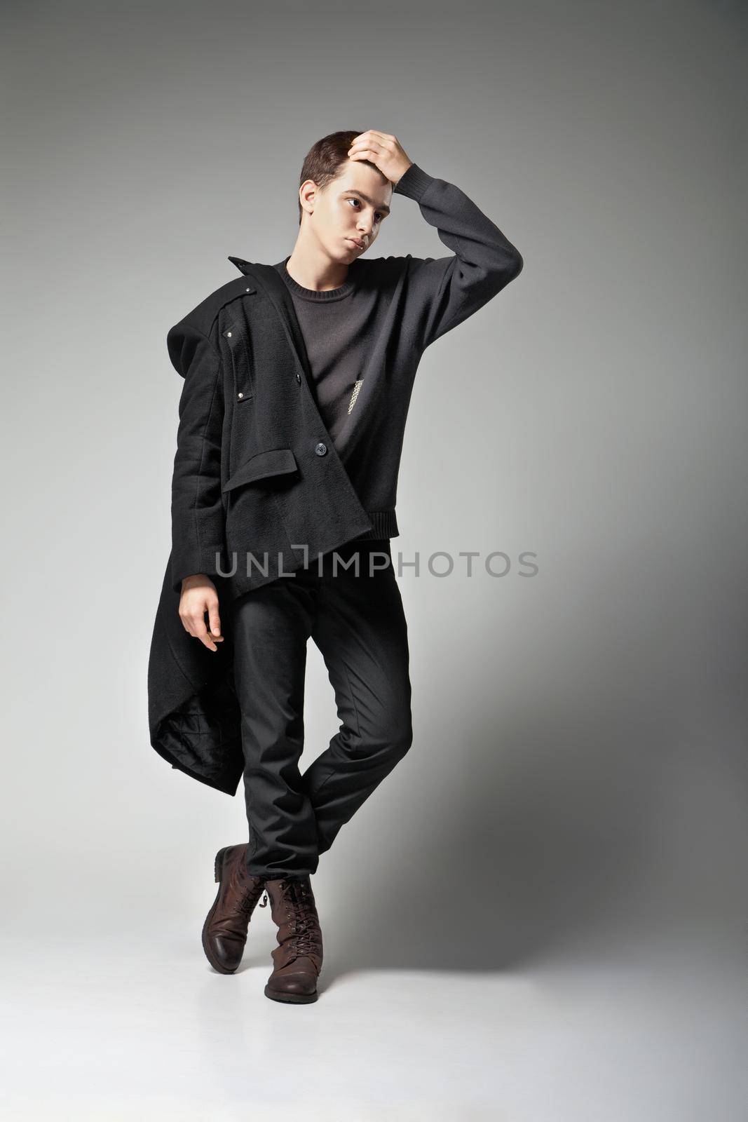 Fashion Shot of a young man in coat on grey background