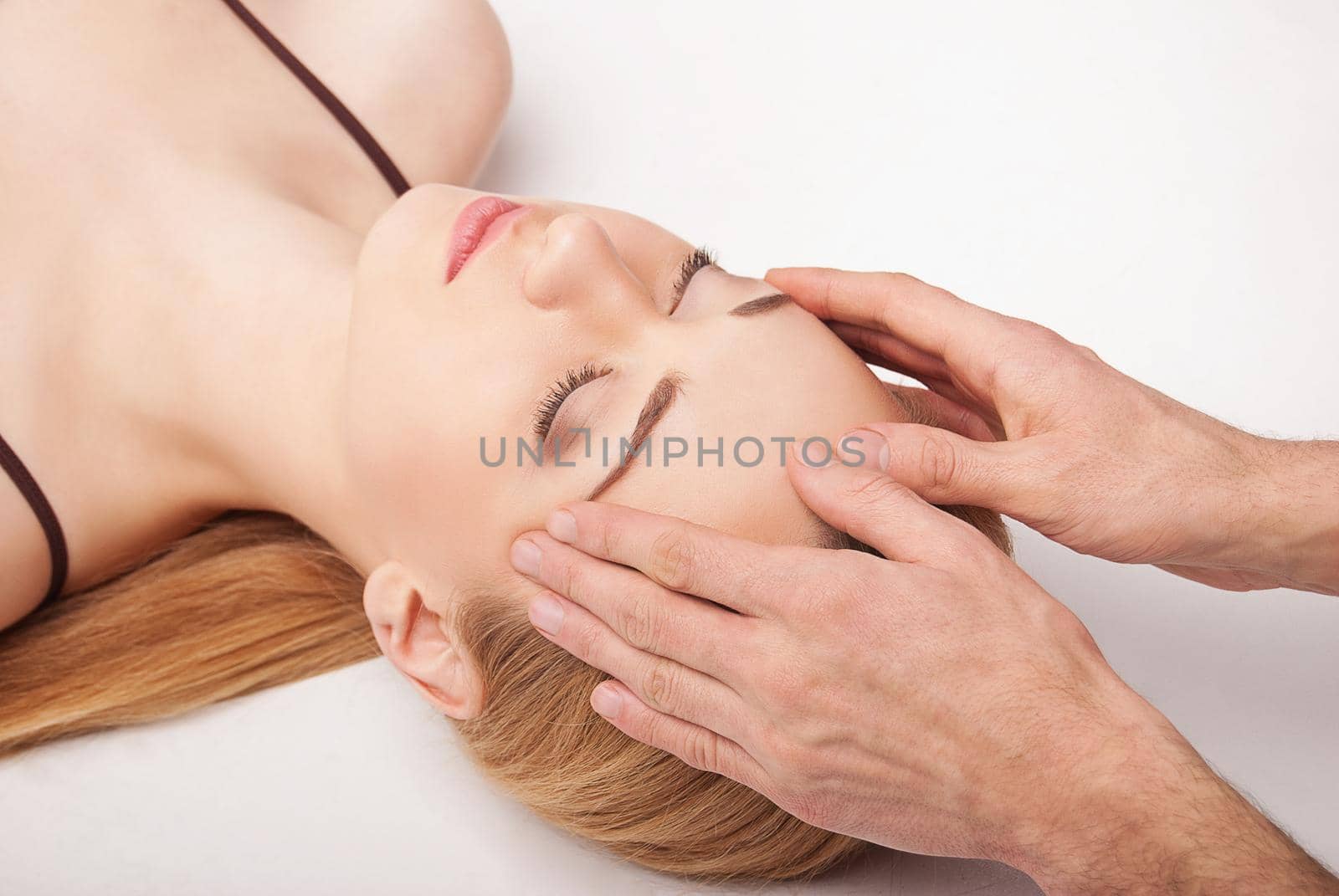 Young woman receiving a head massage on white by Julenochek