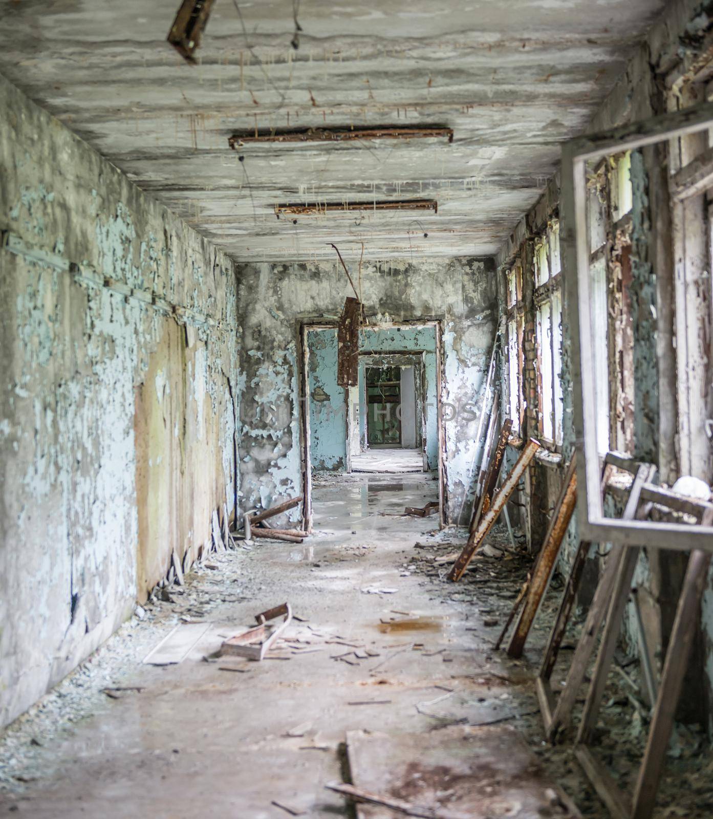 gloomy corridor with broken window frames and debris in Pripyat school