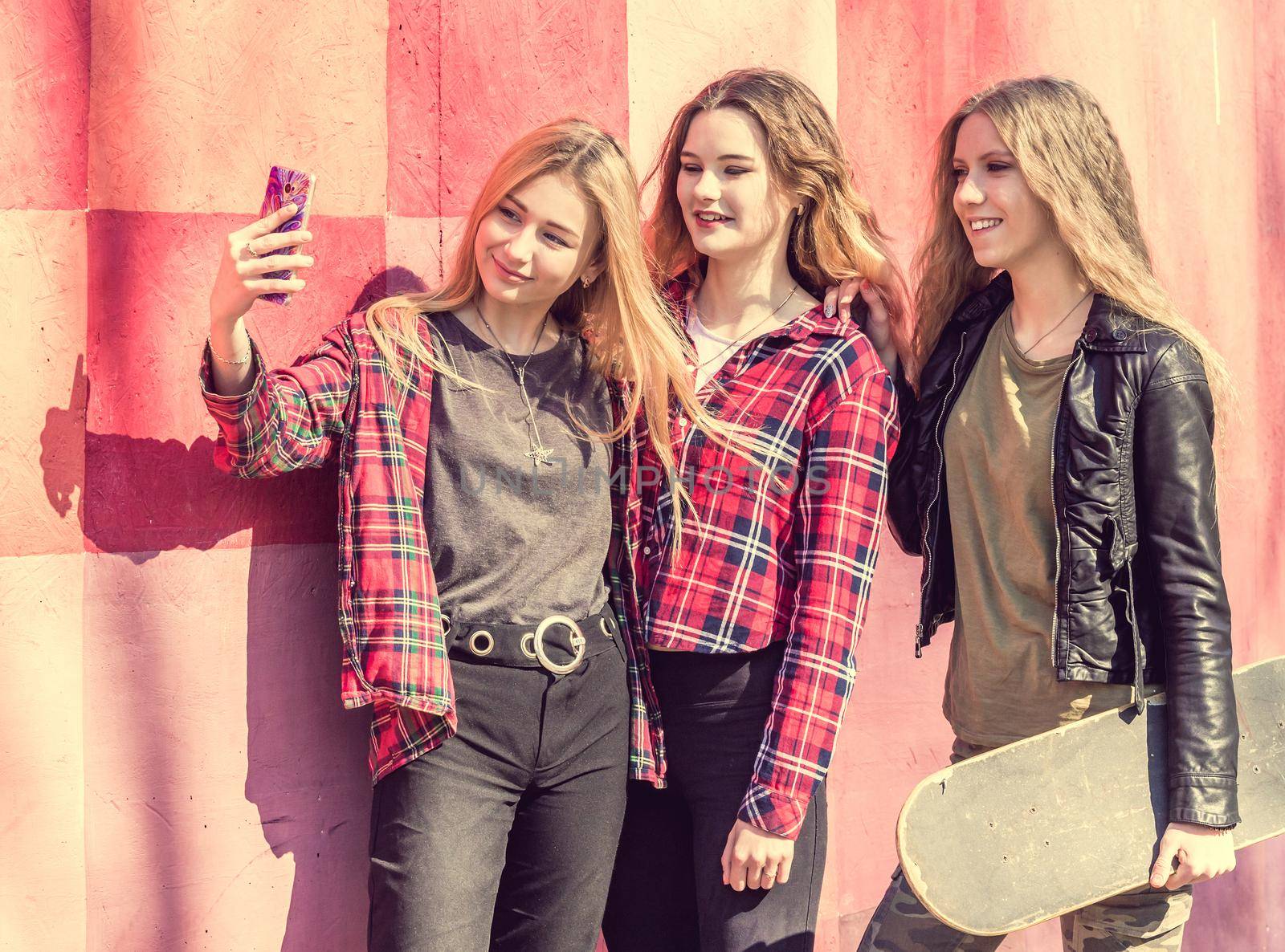 Teenage girls making selfie outdoors while sitting on longboards. Happy friends in the park on a sunny day. Happy friendship concept