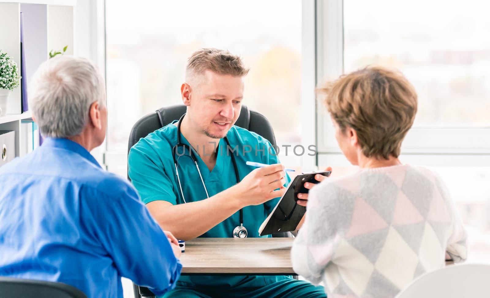 Rear view of mature couple at doctor cabinet during appointment in clinic