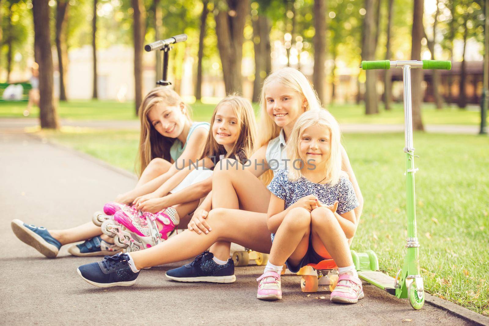 Smiling little girls sitting on the ground in the park by tan4ikk1