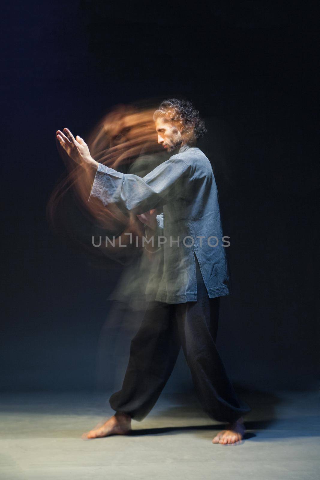 full-length portrait of man in kimono excercising Martial Arts on black bacground with multiexposition