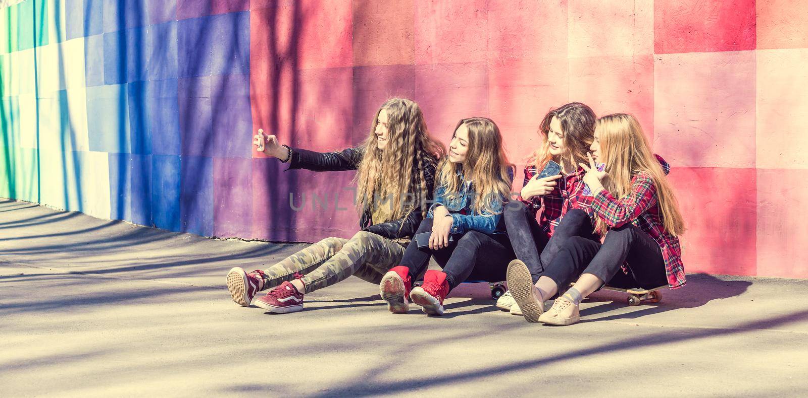 Teenage girls making selfie outdoors while sitting on longboards. Happy friends in the park on a sunny day. Happy friendship concept