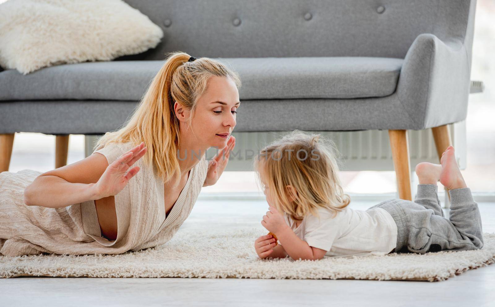 Mother with child son make exercises together laying on the floor at home