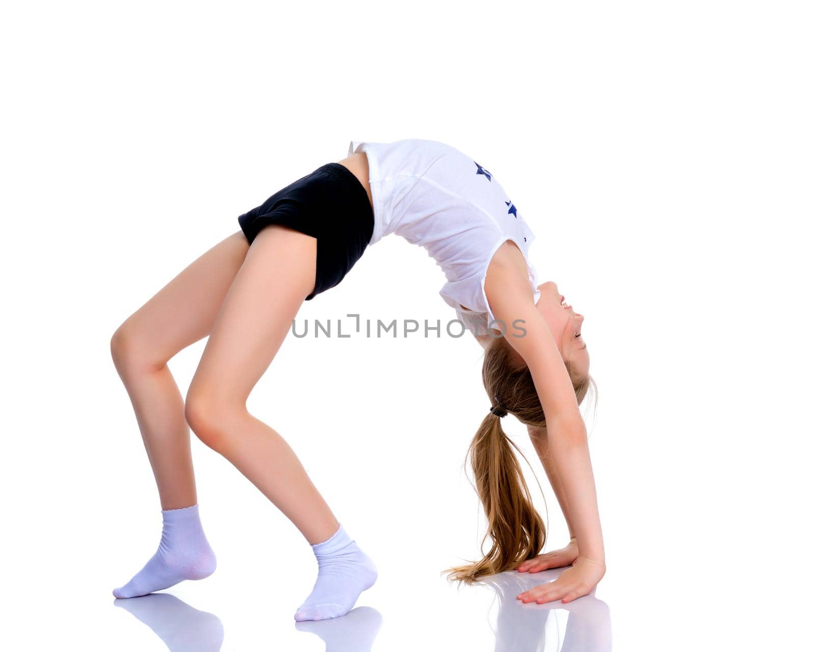 A little girl gymnast performs a bridge. The concept of childhood, sport, healthy lifestyle. Isolated on white background.