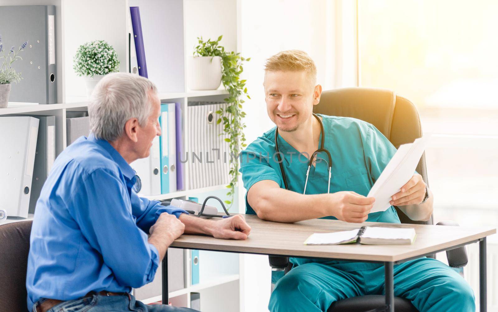 Physician giving recommendations to mature male patient during appointment in clinic