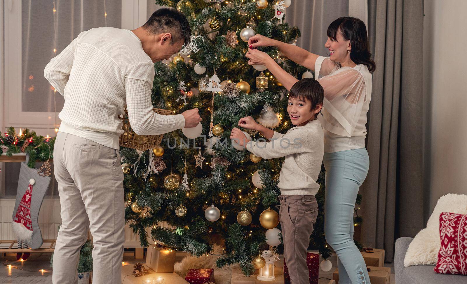 Happy family decorating christmas tree together before celebration at home