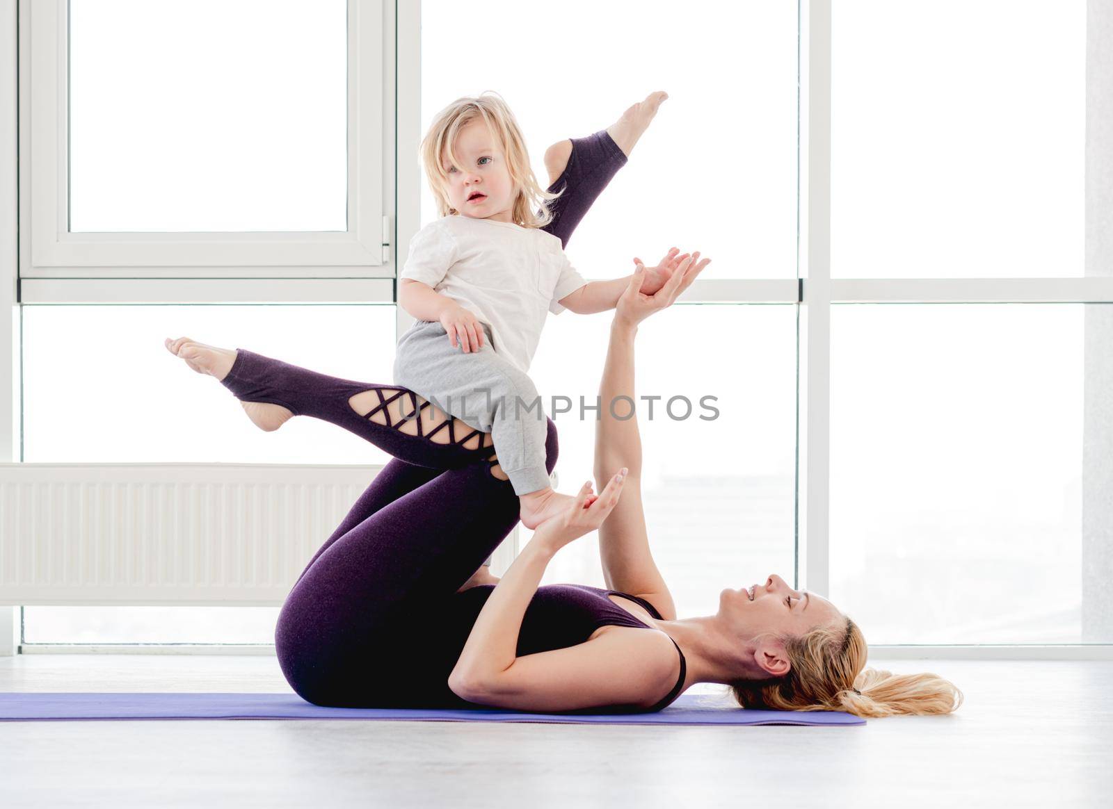 Mother and child practicing yoga by tan4ikk1