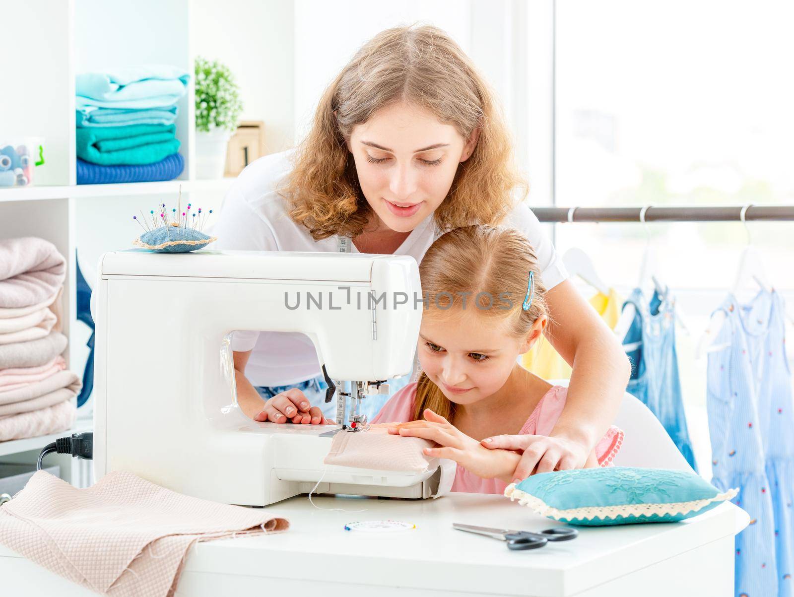 Mother and daughter are sewing on sewing machine at home