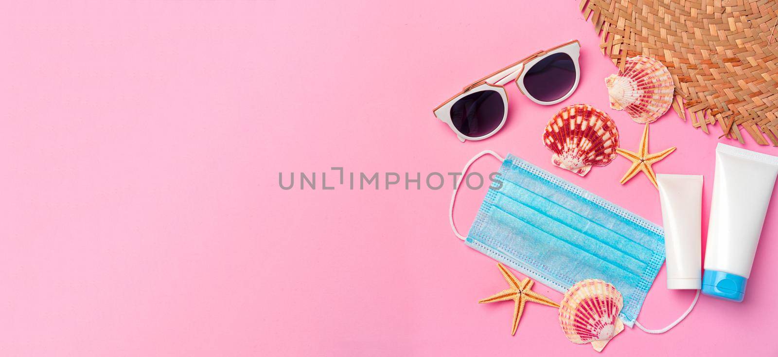 Medical mask with sunscreen cream on pink paper background. Coronavirus summer concept