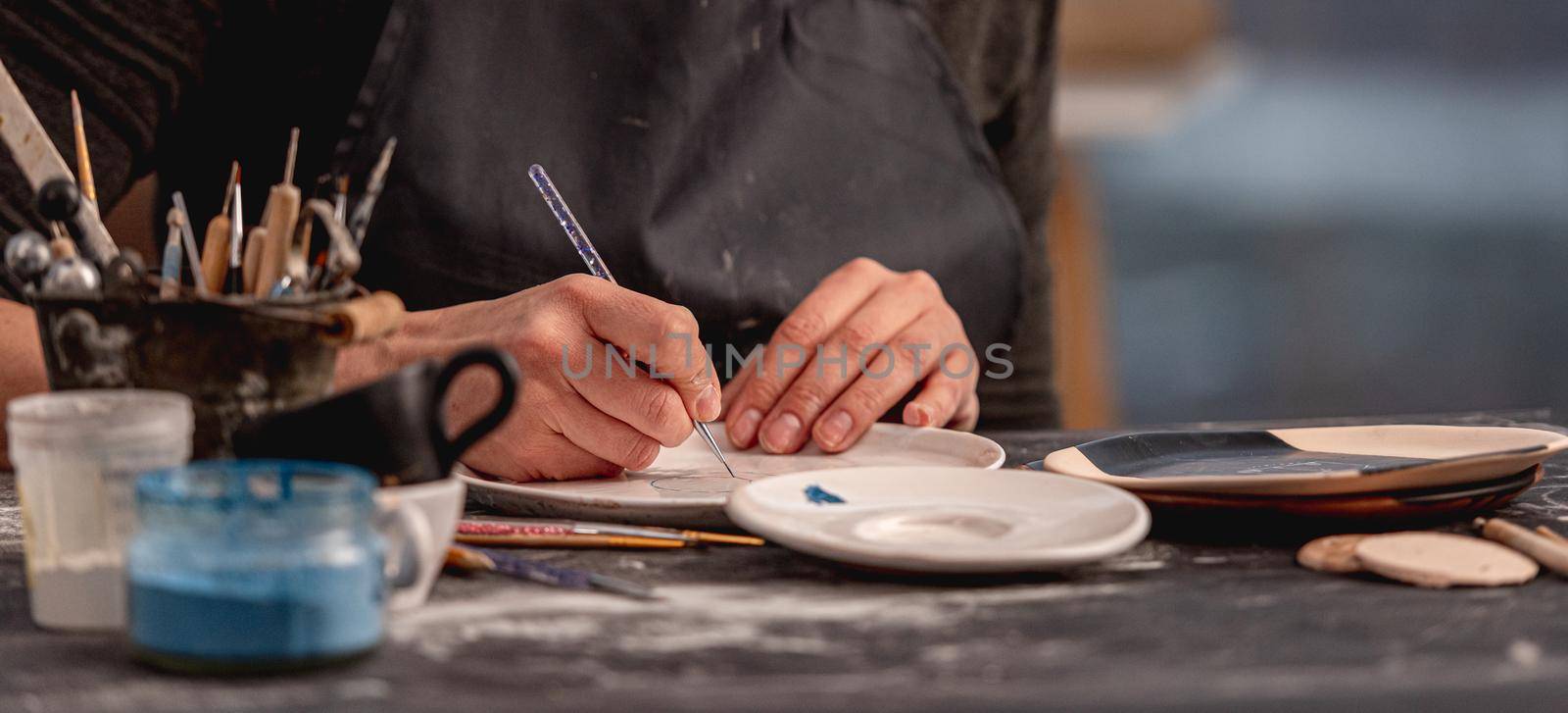 Woman decorating plate with handmade pattern using brush