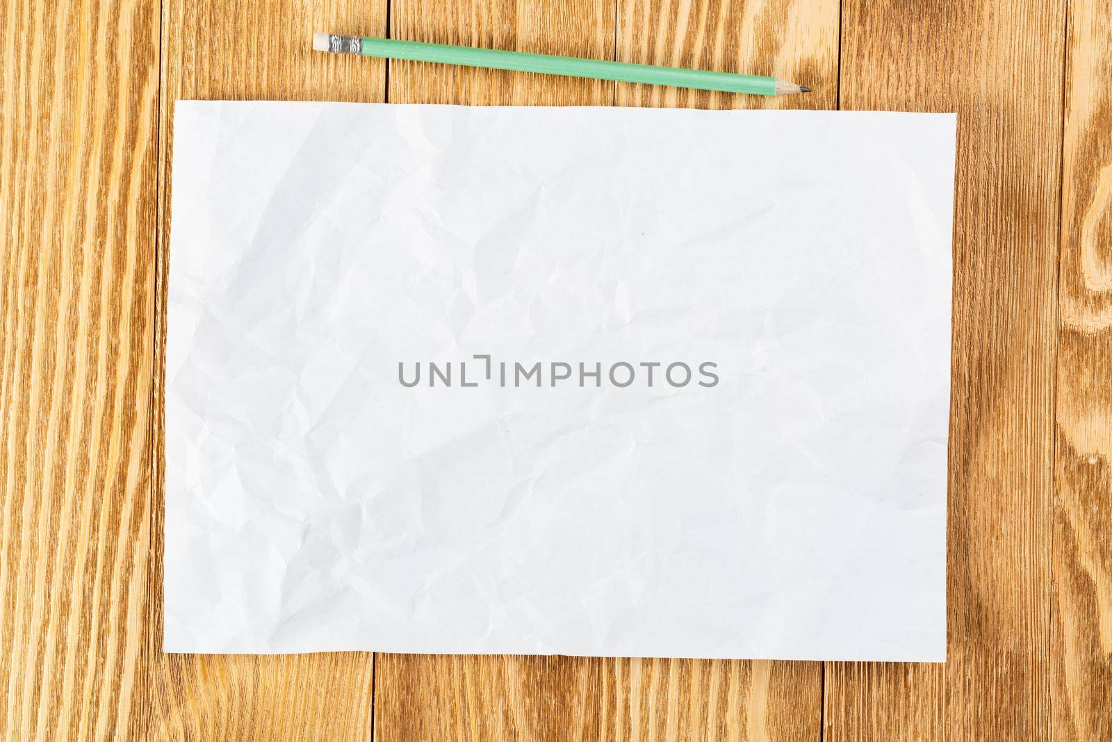 Sheet of paper lying on wooden table. Blank white a4 format paper with pencil. Textured natural wooden background. Vintage copy space for design. Business planning and idea generation.