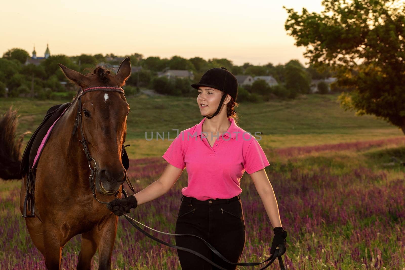 Beautiful young girl smile at her horse dressing uniform competition: outdoors portrait on sunset. Taking care of animals, love and friendship concept.
