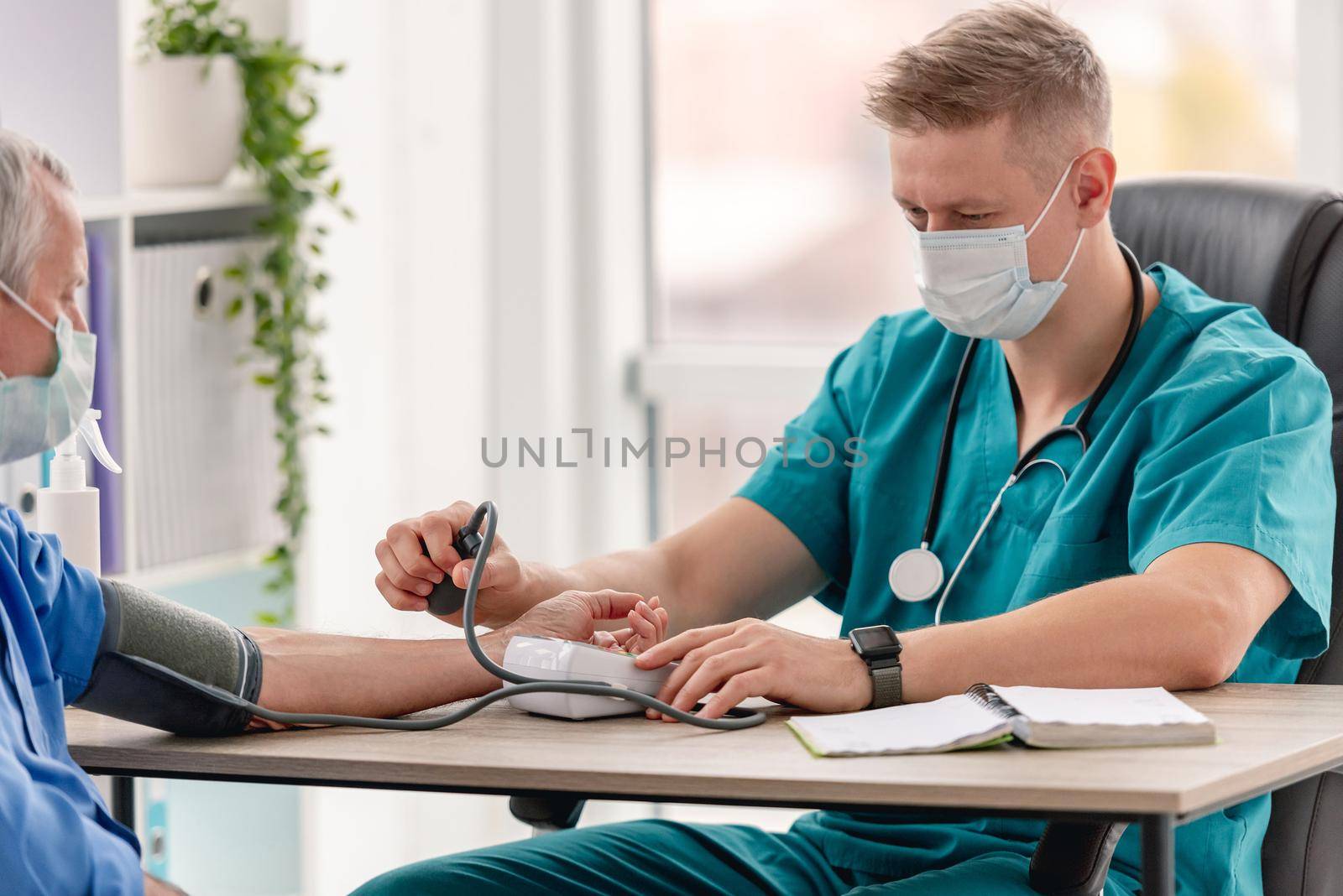 Therapist measuring blood pressure of patient during appointment in clinic