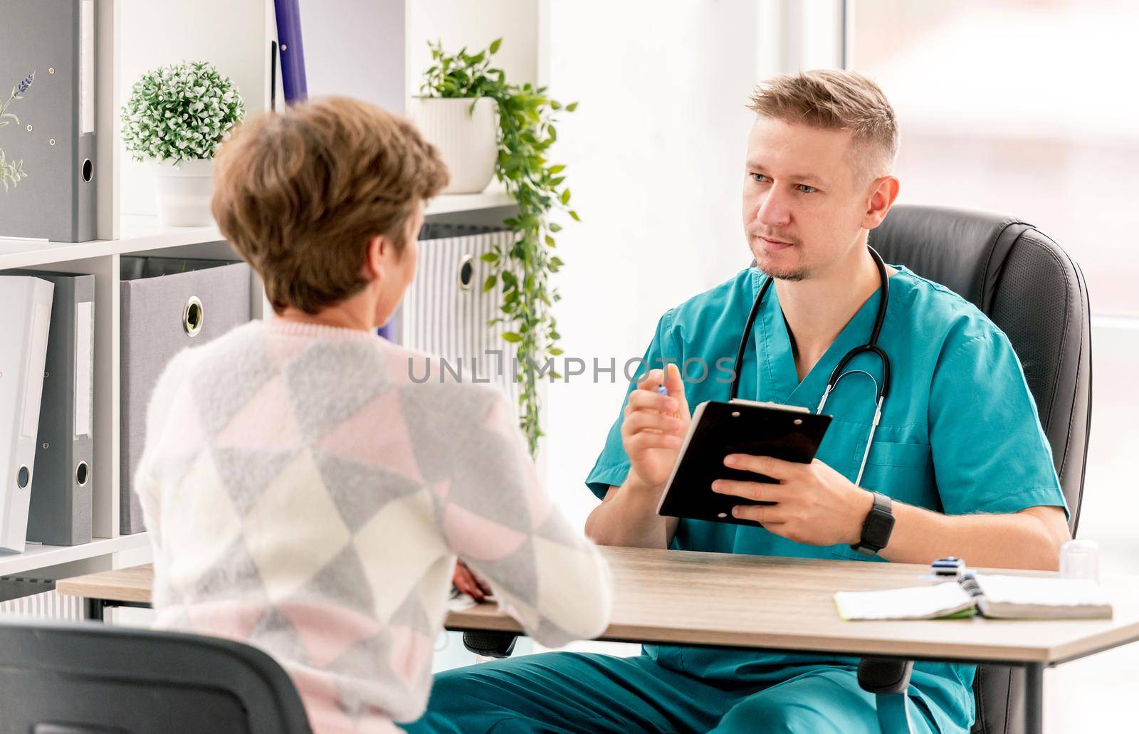 Doctor explaining prescriptions to mature woman patient during appointment in clinic