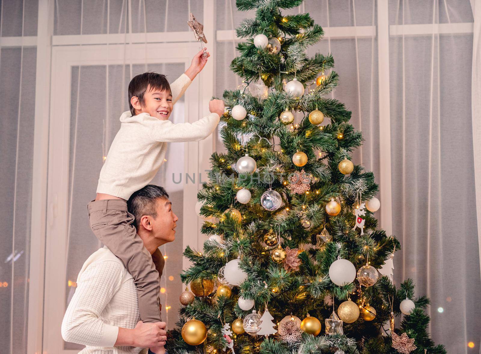 Son and father putting star on tree by tan4ikk1