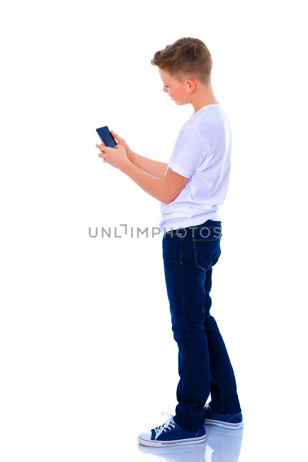 A small boy of school age uses a mobile phone. The concept of digital technology, communication between people. Isolated on white background.