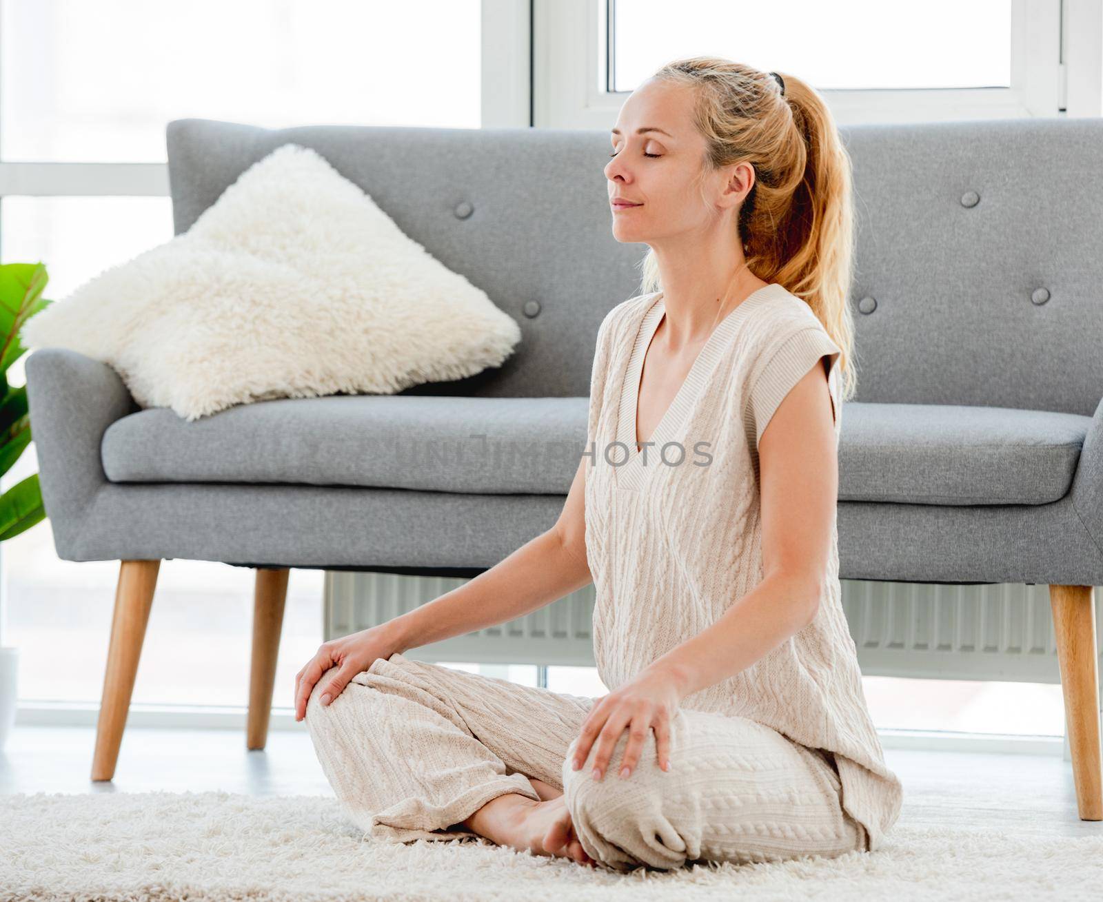 Girl meditates sitting on the floor with legs crossed during morning yoga workout
