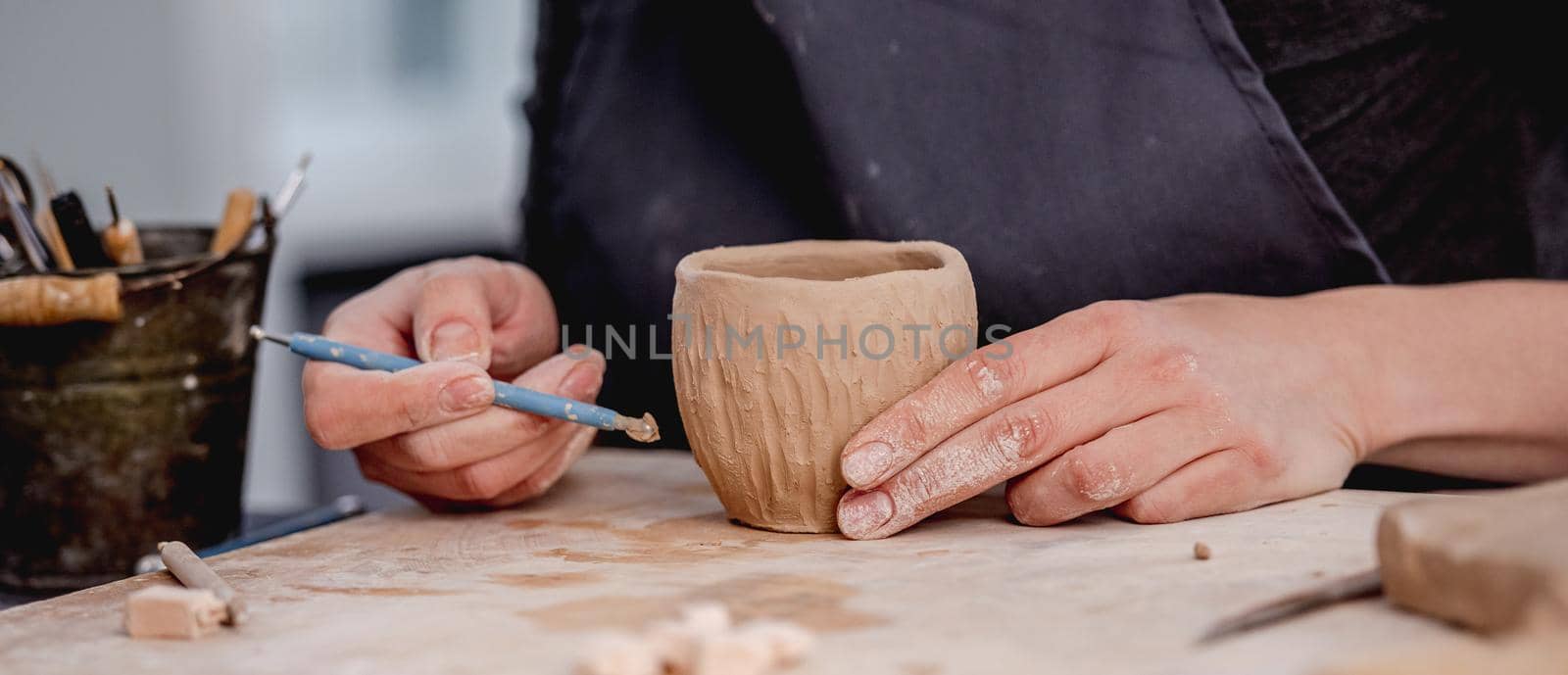Potter using carving tool on mug by tan4ikk1