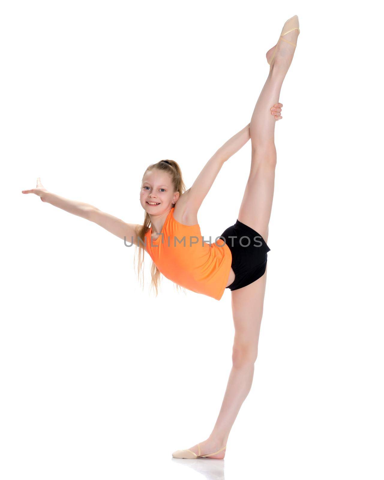 A little girl gymnast performs an exercise: Balance with a grip in the ring. The concept of sport, gymnastics, fitness training, sports development of the child. Isolated on white background.