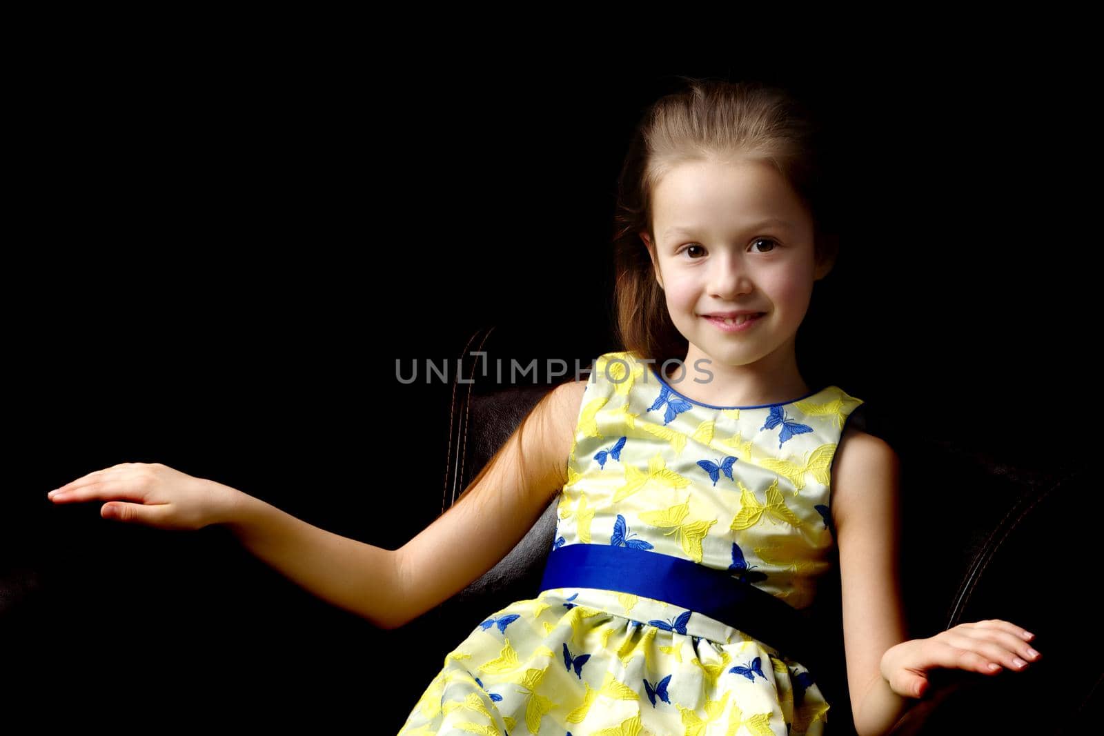 Beautiful little girl, studio portrait on a black background. The concept of a happy childhood, style and fashion.