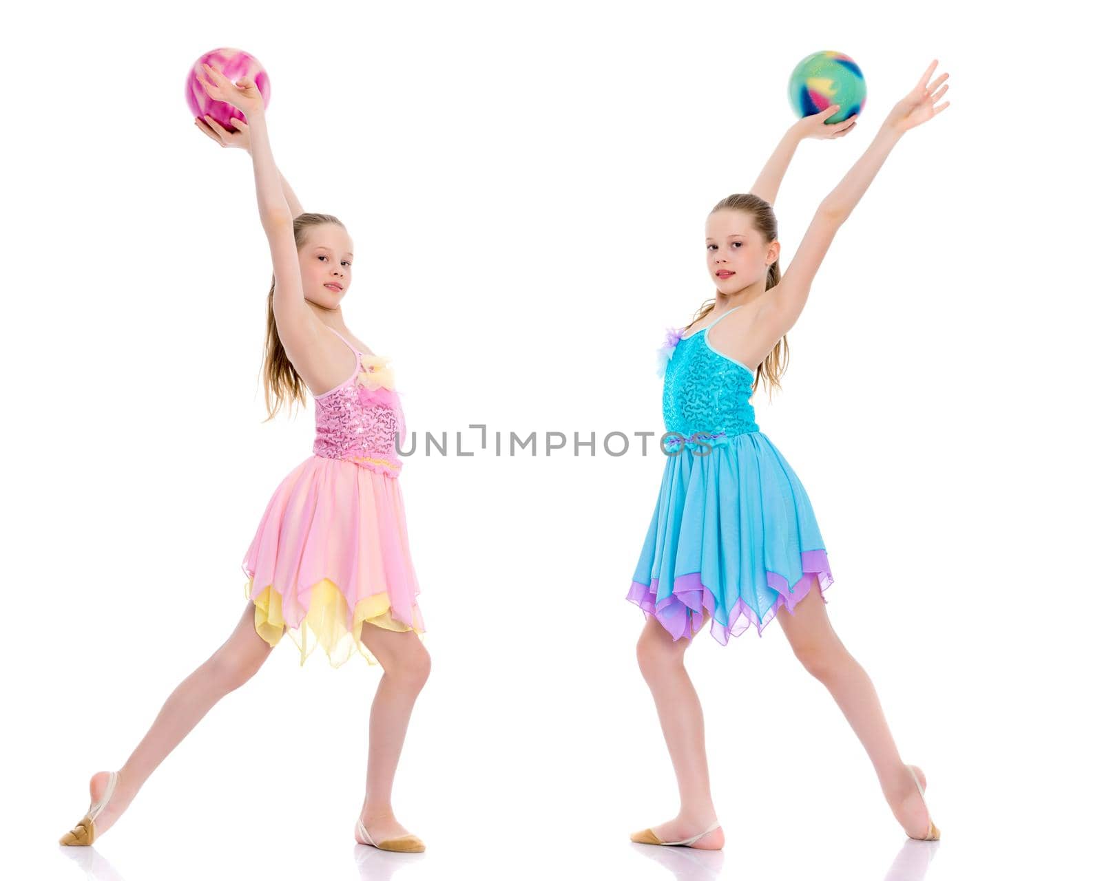 Two cheerful little girls gymnasts in competitions, perform exercises with the ball. The concept of children's sports, fitness, healthy lifestyle. Isolated on white background.