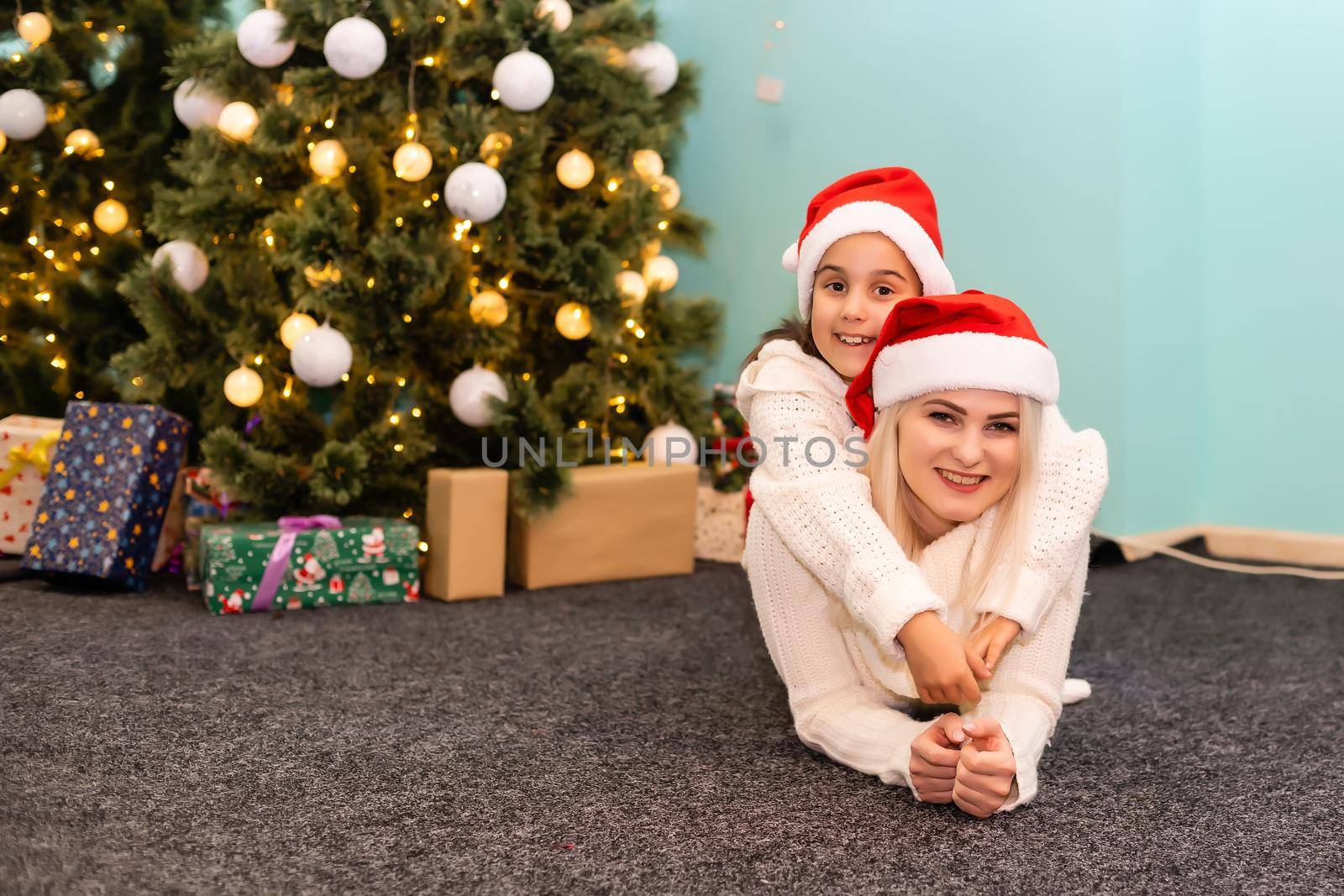 A young and happy mother and daughter in Christmas hats