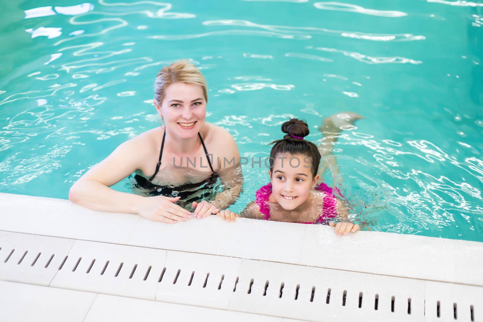 mother and daughter Relaxing By Swimming Pool