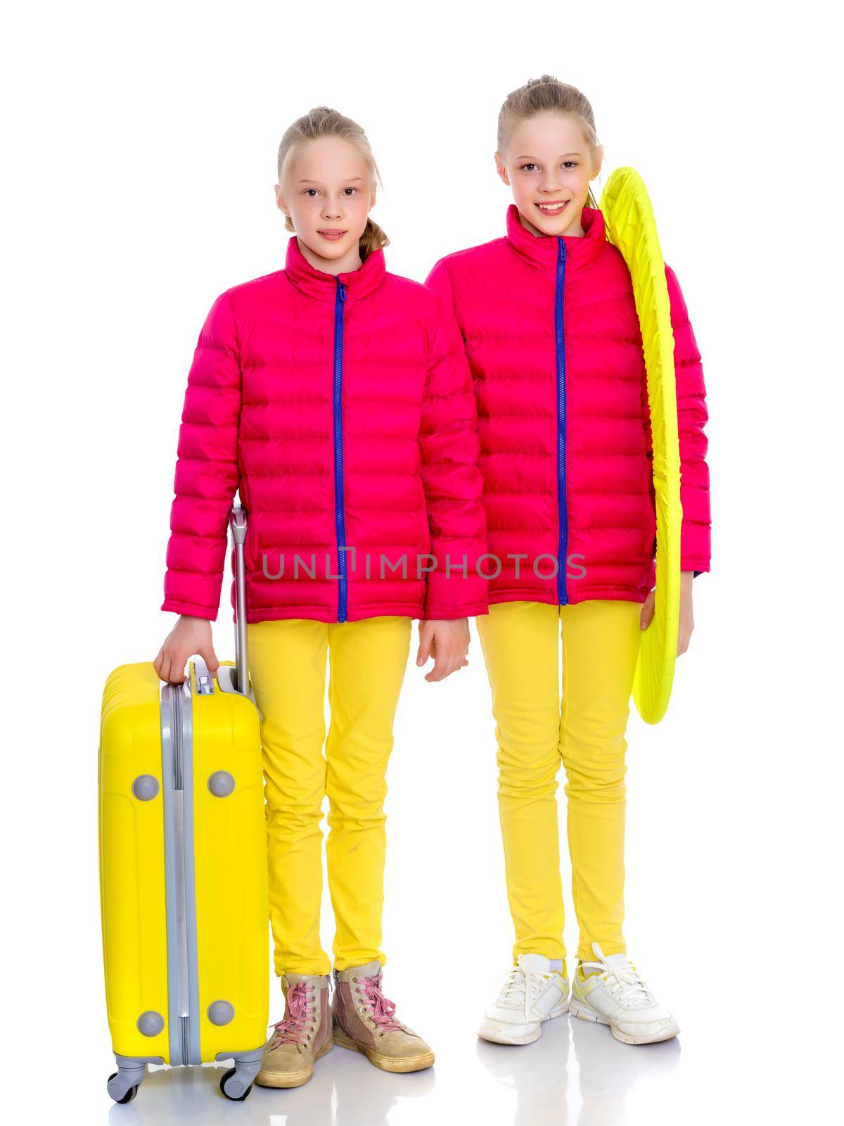 Two cute little girls with large suitcases prepared for the journey. Isolated on white background.