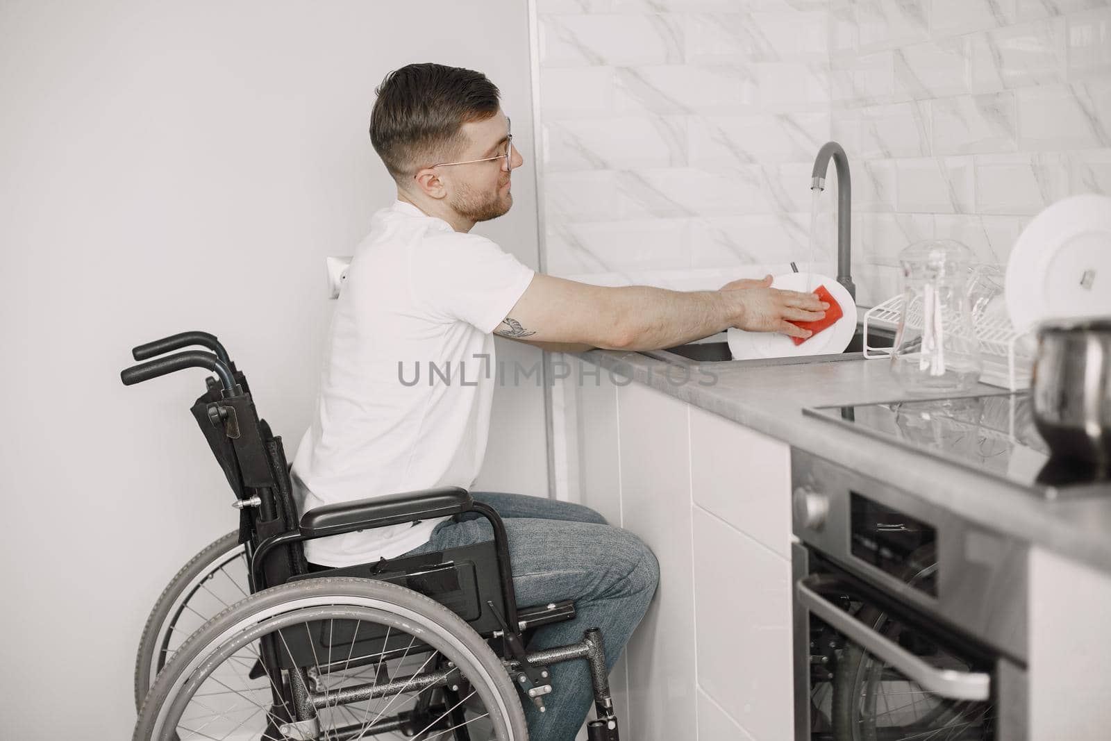 Handicapped Man Cleaning Dishes In Kitchen. Disabled people.